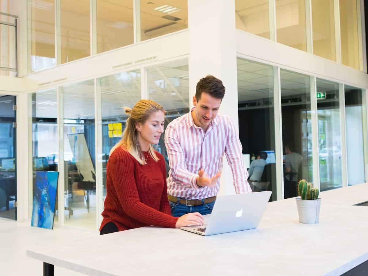 two coworkers discuss a lead generation video on a laptop