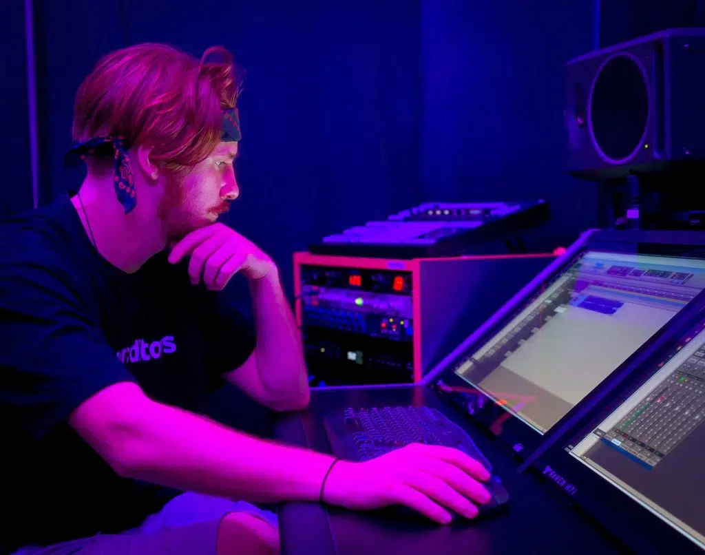 a white man wearing a bandana as a headband edits music for marketing videos