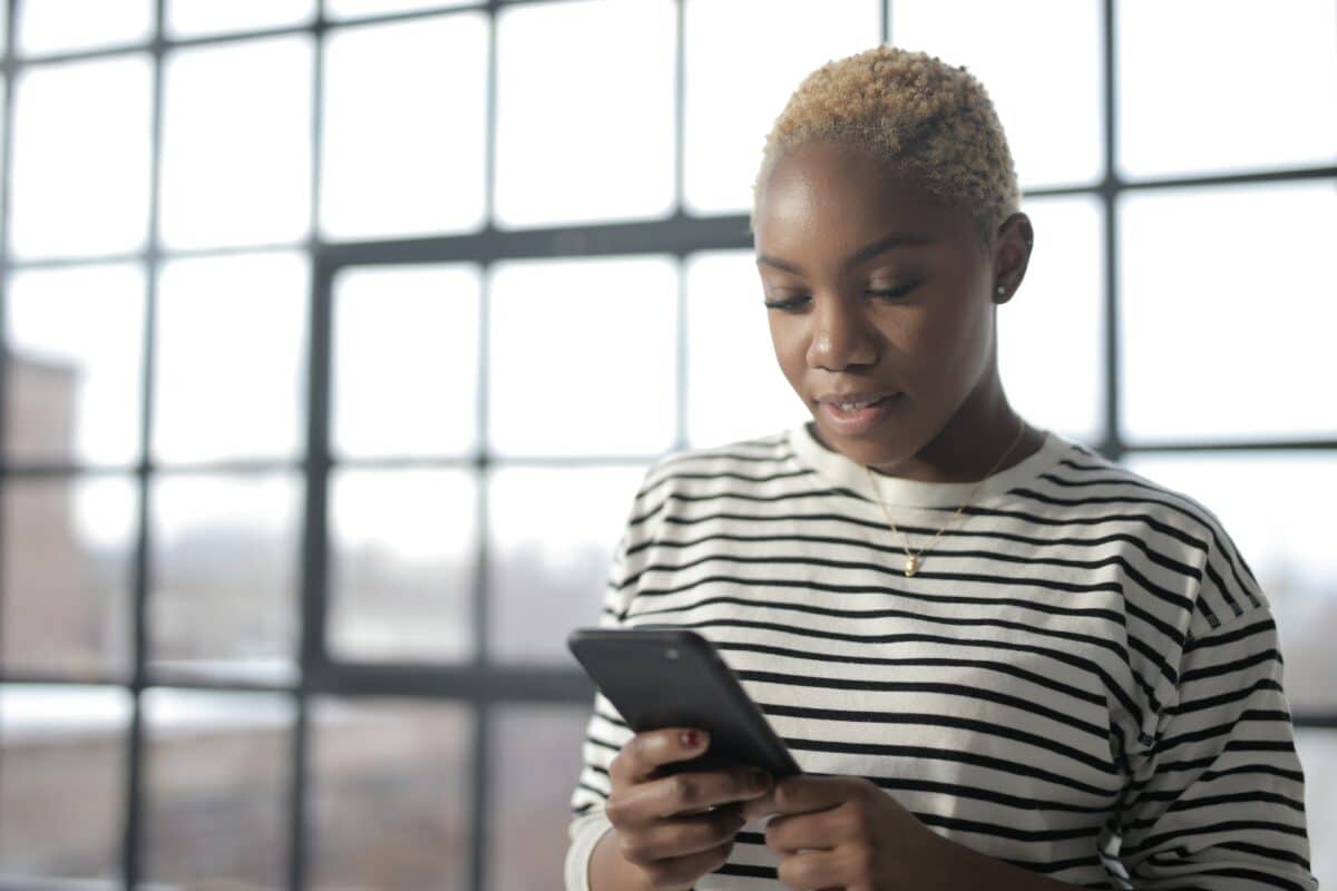 black woman looks at a smartphone