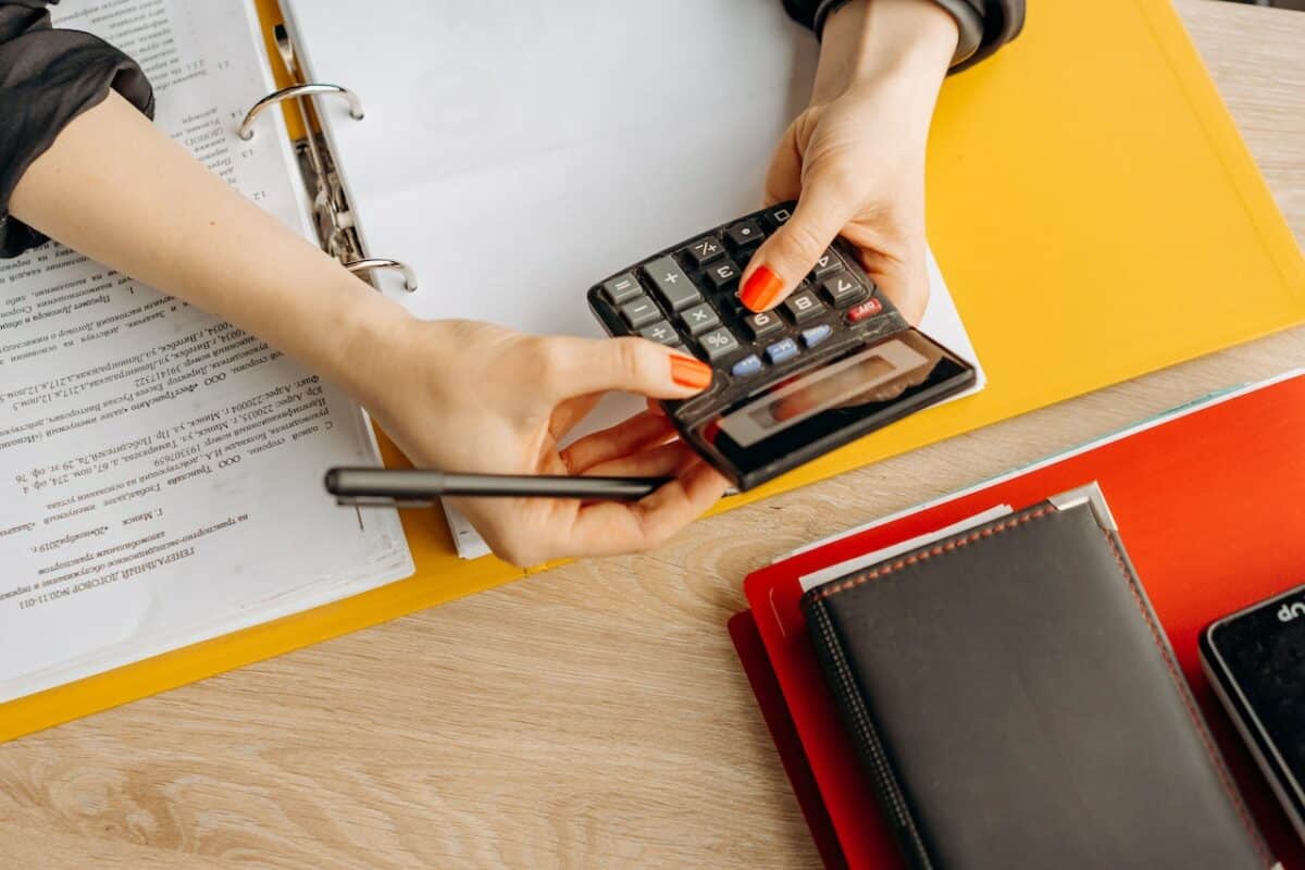 hands with orange finger nails use a calculator