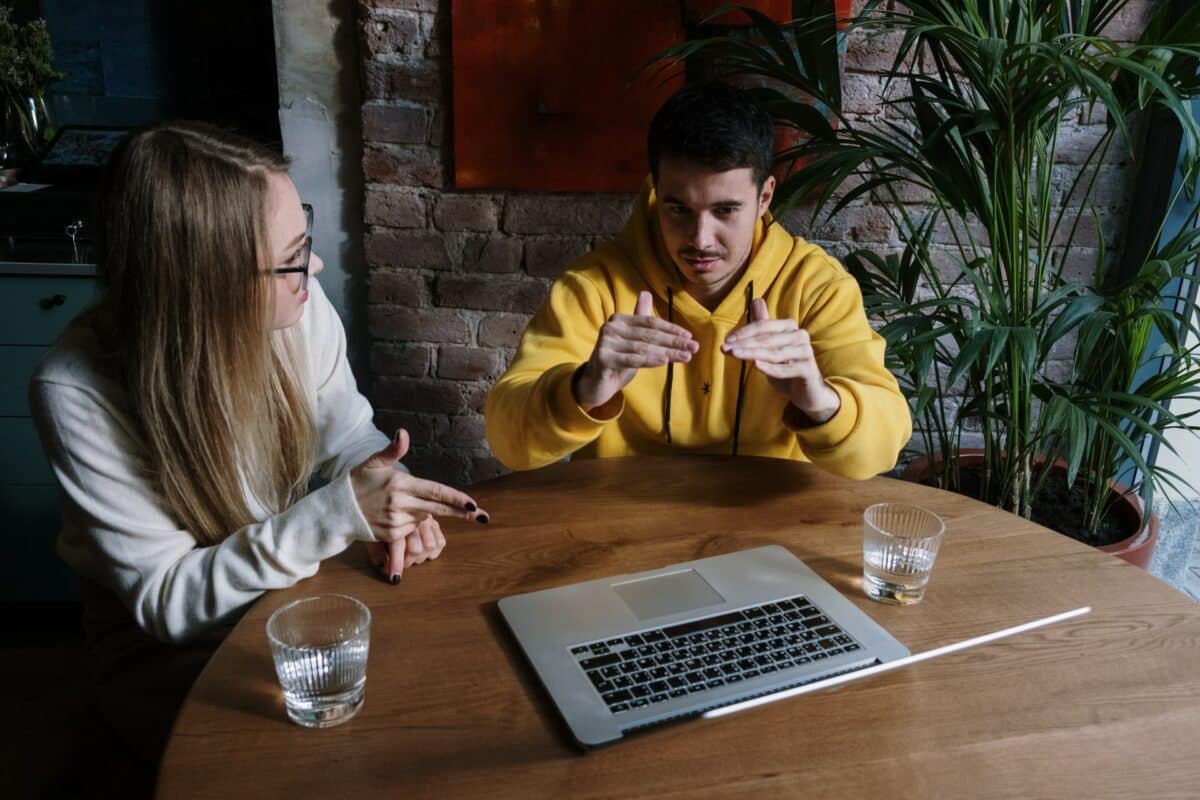 man and woman sit at a table and communicate with sign language