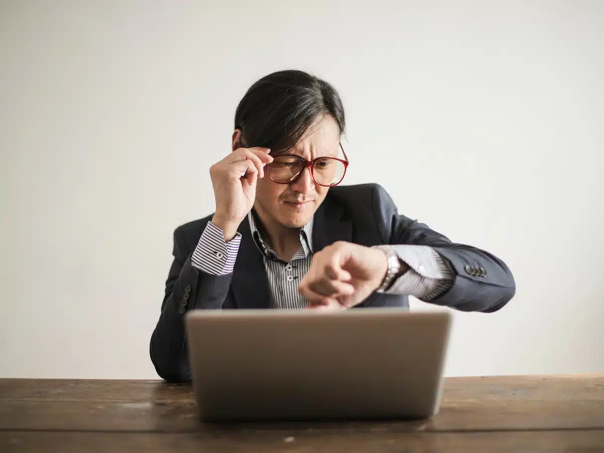 Man looking at his watch while watching a video on his laptop