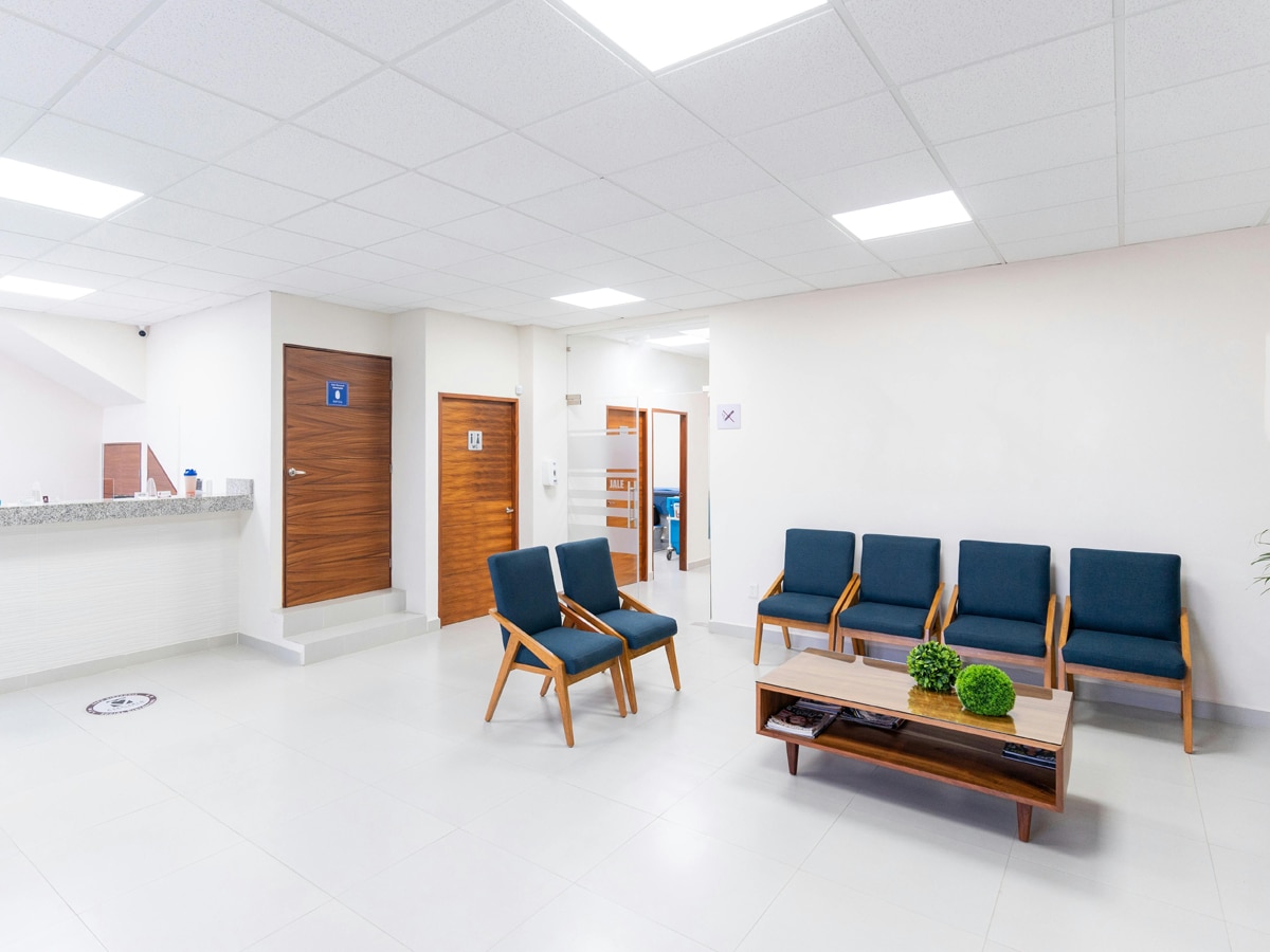 a hospital waiting room with blue chairs and a coffee table